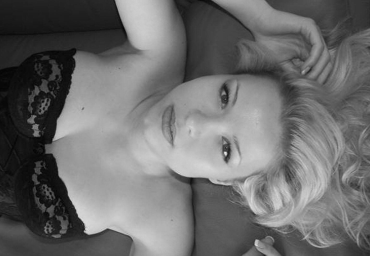 Fotoaufnahme aus einem Portrait-Fotoshooting mit blondem Fotomodell in schwarzen Dessous (Home-Shooting)
